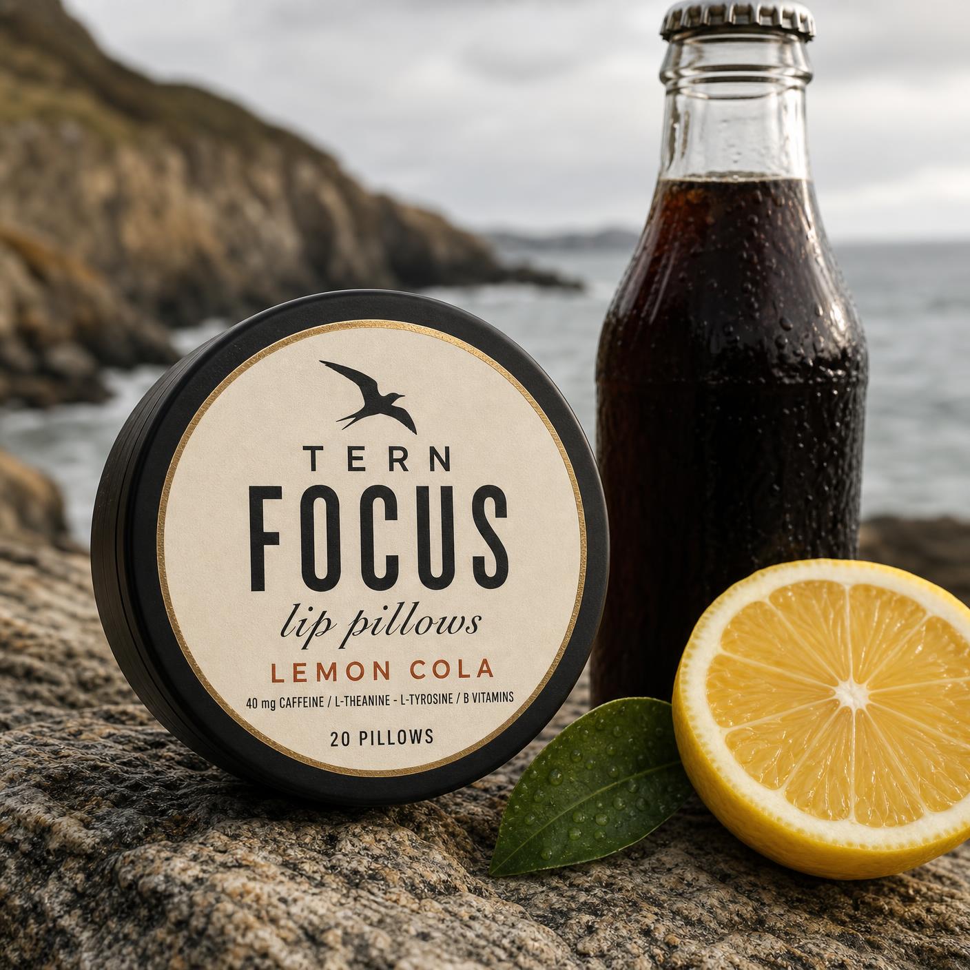TERN FOCUS lip pillows in Lemon Cola, resting on coastal granite beside a cola bottle and lemon